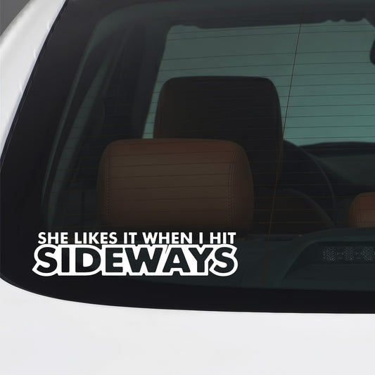 White "She likes it when I hit it sideways" vinyl sticker applied to a car window.