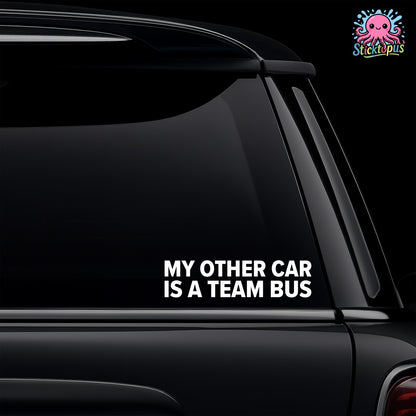 Car window with a decal saying 'My other car is a team bus' on a black background.