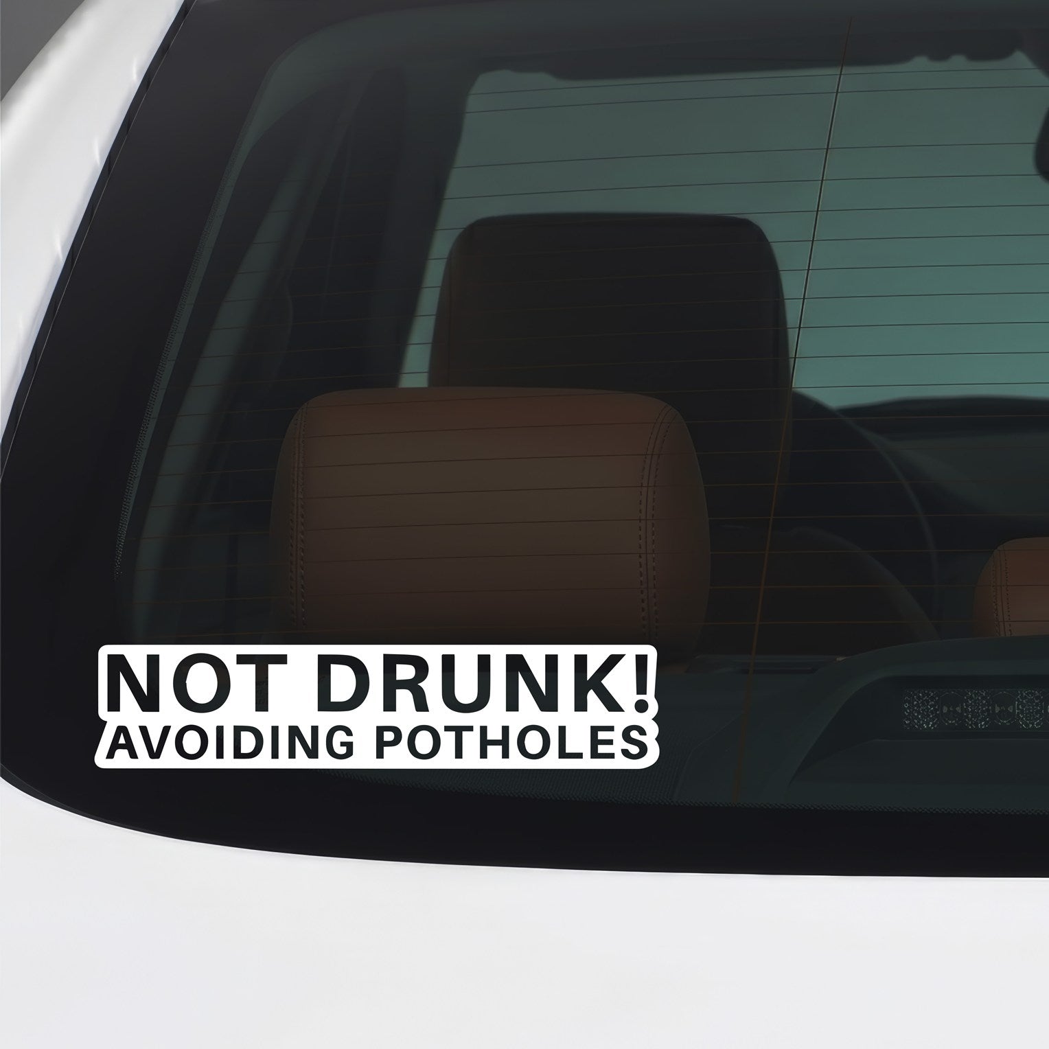 White Not Drunk Avoiding Potholes sticker applied to a car window.
