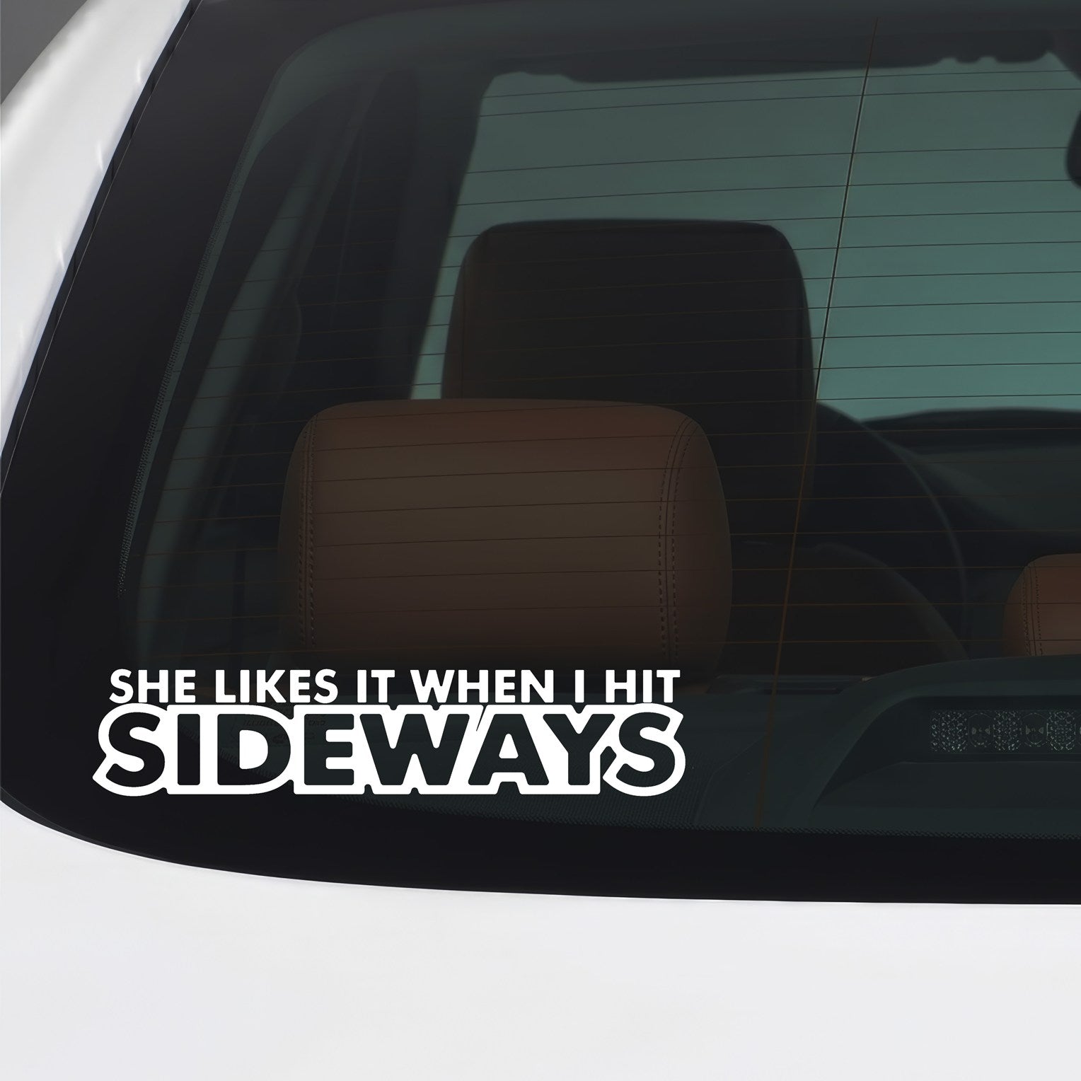 White "She likes it when I hit it sideways" vinyl sticker applied to a car window.